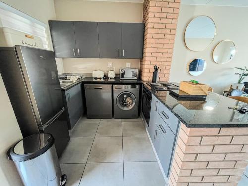 a small kitchen with a washer and dryer in it at The Ridge Modern Escape in Midrand