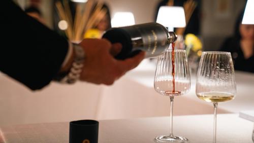 a person pouring white wine into two wine glasses at Altafiumara Resort & Spa in Villa San Giovanni