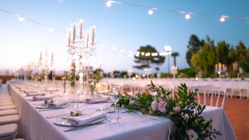 a long table with plates and glasses and flowers on it at Altafiumara Resort & Spa in Villa San Giovanni