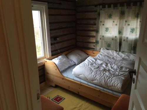 a small bed in a room with a window at Cottage Lavkavann Finnmarksvidda in Skoganvarre
