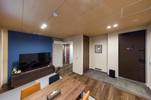 a living room with a large television and a wooden table at Culture villa HANEDA in Tokyo