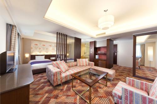 a hotel room with a couch and a bed at Kokusai 21 International Hotel in Nagano