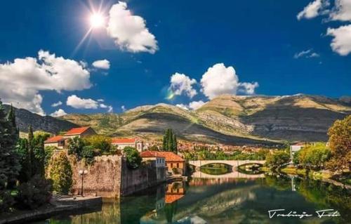 a painting of a town with a river and mountains at Apartman CENTAR in Trebinje