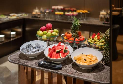 a table with bowls of fruit and bowls of other fruits at Orange Crystal Hotel MixC Shantou East Coast in Shantou