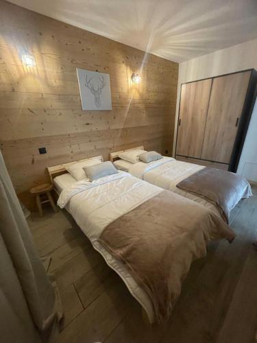 Cette chambre dispose de 2 grands lits dans une chambre dotée de murs en bois. dans l'établissement Cozy & modern apartment, à Samoëns