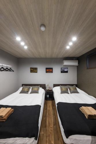 two beds in a room with a wooden ceiling at Culture villa HANEDA in Tokyo