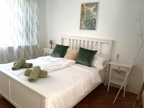a bedroom with a white bed with green pillows at Apartment Daisy in Vantačići