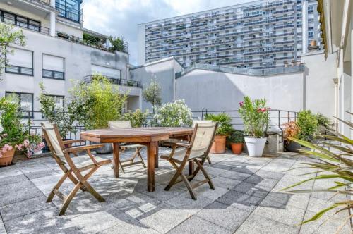 une table et des chaises en bois sur une terrasse dans l'établissement magnificent studio2CheckProfile, à Paris