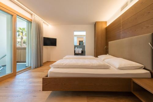 a bedroom with two beds and a large window at Appartement KroneLiving in Tirolo