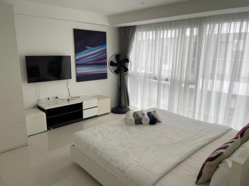a white bedroom with a large bed and a large window at Sunset Plaza in Ban Karon