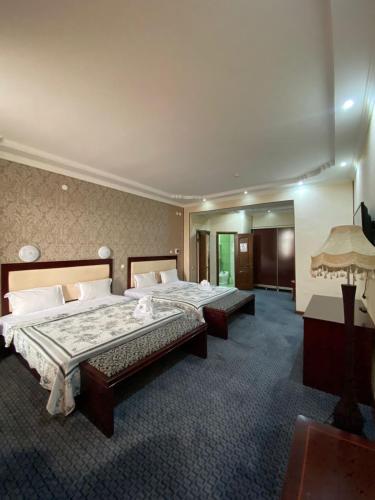 a hotel room with two beds and a mirror at Sary Arka Hotel in Shymkent