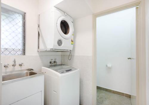 a white kitchen with a sink and a microwave at Citi Serviced Apartments - Gaba Place in Port Moresby
