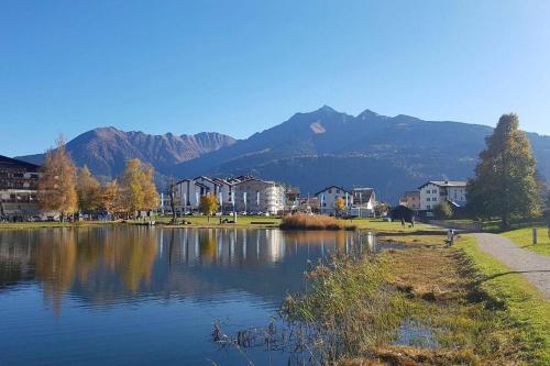 a lake with houses and mountains in the background at Via Valla - Spacious Open-plan and Peaceful Chalet in Salums in Laax