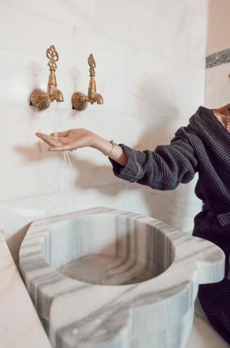 a woman is reaching for a bathroom sink at The Local House Alaçatı in Alacati