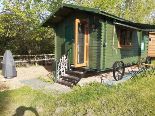 a green tiny house with a porch and stairs at Glamping Malvern shepherd hut in Malvern Link