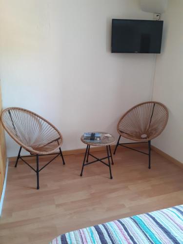two chairs and a table in a room with a tv at auberge saint roch in Beaumes-de-Venise