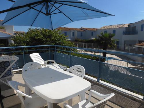 une table et des chaises avec un parasol sur un balcon dans l'établissement Appartement tout confort dans résidence avec piscine, à Vaux-sur-Mer
