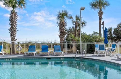 a swimming pool with blue chairs and palm trees at Ocean Blue 902 in Myrtle Beach