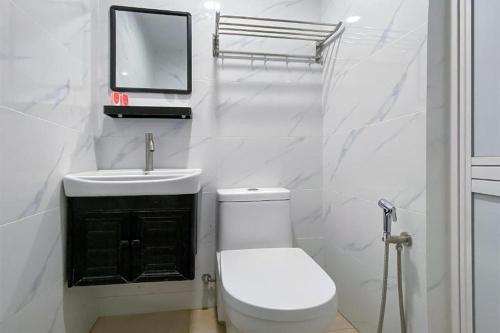 a white bathroom with a toilet and a sink at Coop Hotel Kangar in Kangar