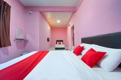 a pink bedroom with a large bed with red pillows at Coop Hotel Kangar in Kangar