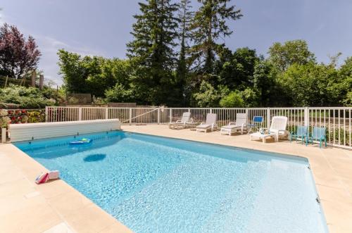 a large swimming pool with chairs and a fence at Le gite du petit ecureuil in Balnot-sur-Laignes