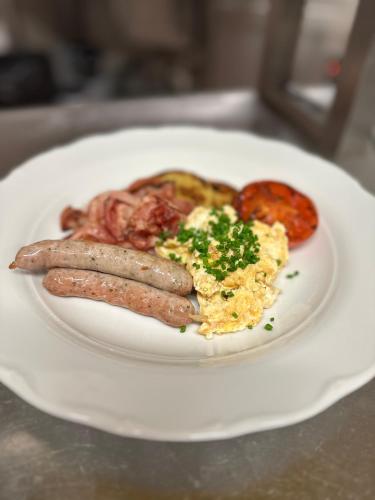 a plate of breakfast food with sausage and eggs at Penzion Tlustá kachna in Chrudim