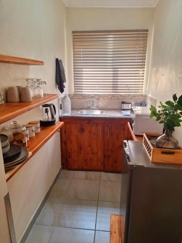 a kitchen with wooden cabinets and a sink and a window at Fraai Maraai Self Catering Apartments in Groblersdal