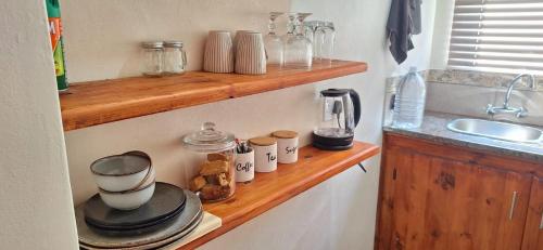 a kitchen with a wooden shelf with cups and cookies at Fraai Maraai Self Catering Apartments in Groblersdal