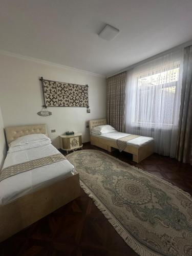 a bedroom with two beds and a window and a rug at Sultan Saray in Osh