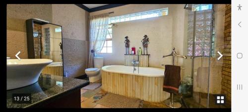 een badkamer met een bad, een toilet en een wastafel bij Kamga House in Bloemfontein