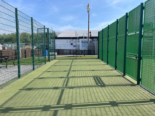 an empty tennis court with a green fence at The Dean's on the Lune in Heysham
