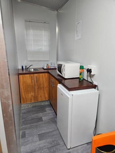 a small kitchen with a microwave and a refrigerator at MKHUZE INN in Mkuze