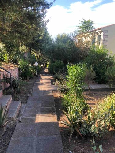 a pathway in a garden with plants and trees at Grandpà apartment in residence with swimming pool in Badesi