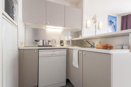 a kitchen with white cabinets and a dishwasher at Résidence Antarès - Avoriaz in Morzine