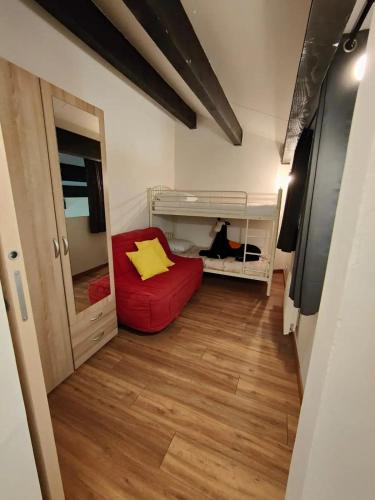 une petite pièce avec un canapé rouge et un lit superposé dans l'établissement Appartement cocooning, aux Angles