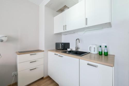a kitchen with white cabinets and a sink at Waterlane Island Deluxe 5B by Grand Apartments in Gdańsk