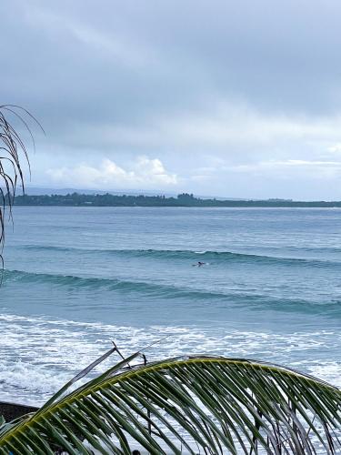 a person riding a wave in the ocean at Baia Nest TURINGAN Loft, Self-Service Breakfast, Near the Beach, Pet Friendly with a Fee in Gubat