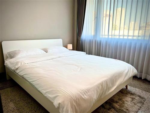 a white bed in a bedroom with a window at The Circle 4 in Bangkok