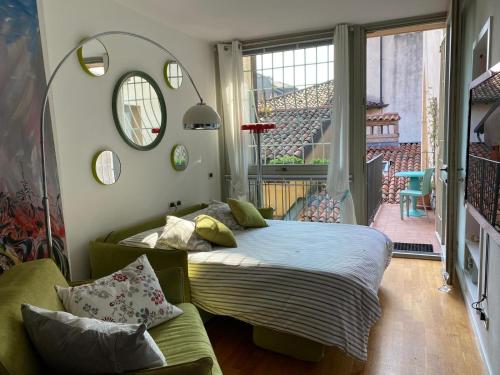 a bedroom with a bed and a couch and a window at La Casetta sui tetti in Bergamo