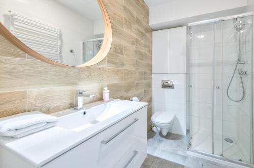 a bathroom with a sink and a shower and a mirror at Waterlane Island Deluxe 5A by Grand Apartments in Gdańsk