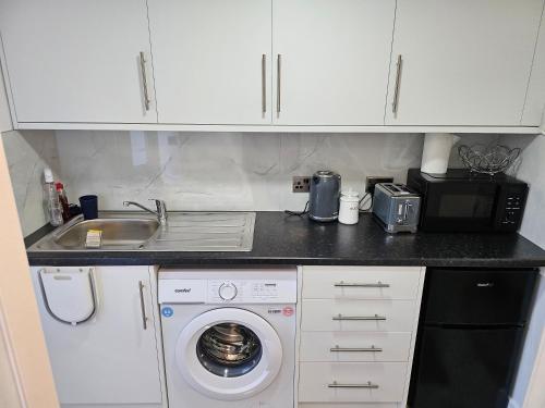 a kitchen with a washing machine and a microwave at Muhazee Lodge in Orton Waterville