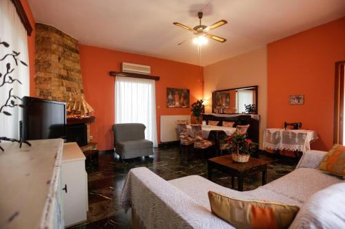 a living room with orange walls and a couch and a television at Marousa's Country House 12 minutes from Athens Airport in Koropíon