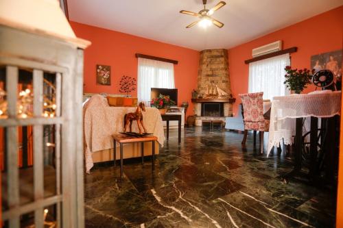 a living room with orange walls and a fireplace at Marousa's Country House 12 minutes from Athens Airport in Koropíon