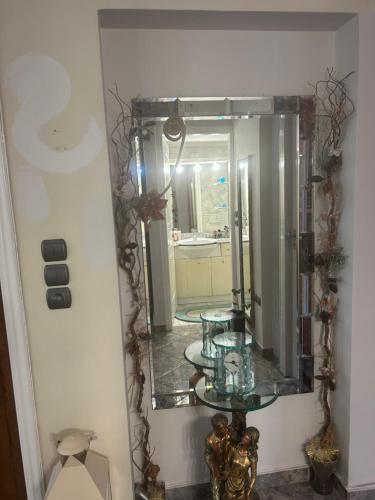 a mirror on a wall with a table in a room at Mandy's cosy luxury flat in Piraeus