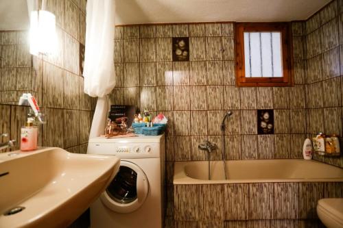 a bathroom with a tub and a washing machine and a sink at Marousa's Country House 12 minutes from Athens Airport in Koropíon