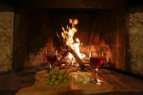 a fireplace with two glasses of wine and grapes at Marousa's Country House 12 minutes from Athens Airport in Koropíon