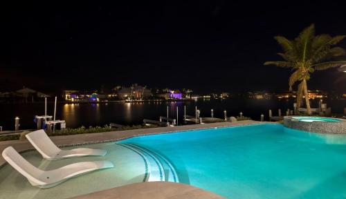a swimming pool at night with two chairs and the water at Meridian Blu in Marco Island