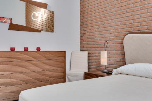 a bedroom with a white bed and a brick wall at Casa Gardenia -affittacamere in Gatteo