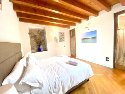 a bedroom with a large white bed with wooden ceilings at Wohnung Mit Privatem Garten Und Schöner Aussicht in Moniga