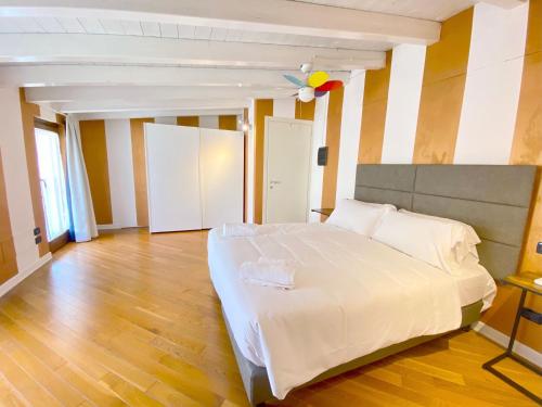 a bedroom with a large white bed and a wooden floor at Wohnung Mit Privatem Garten Und Schöner Aussicht in Moniga